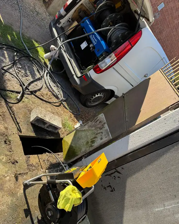 Caméra d'inspection de MD Débouchage installée près d'un regard d'égout ouvert, camionnette d'intervention à l'arrière-plan